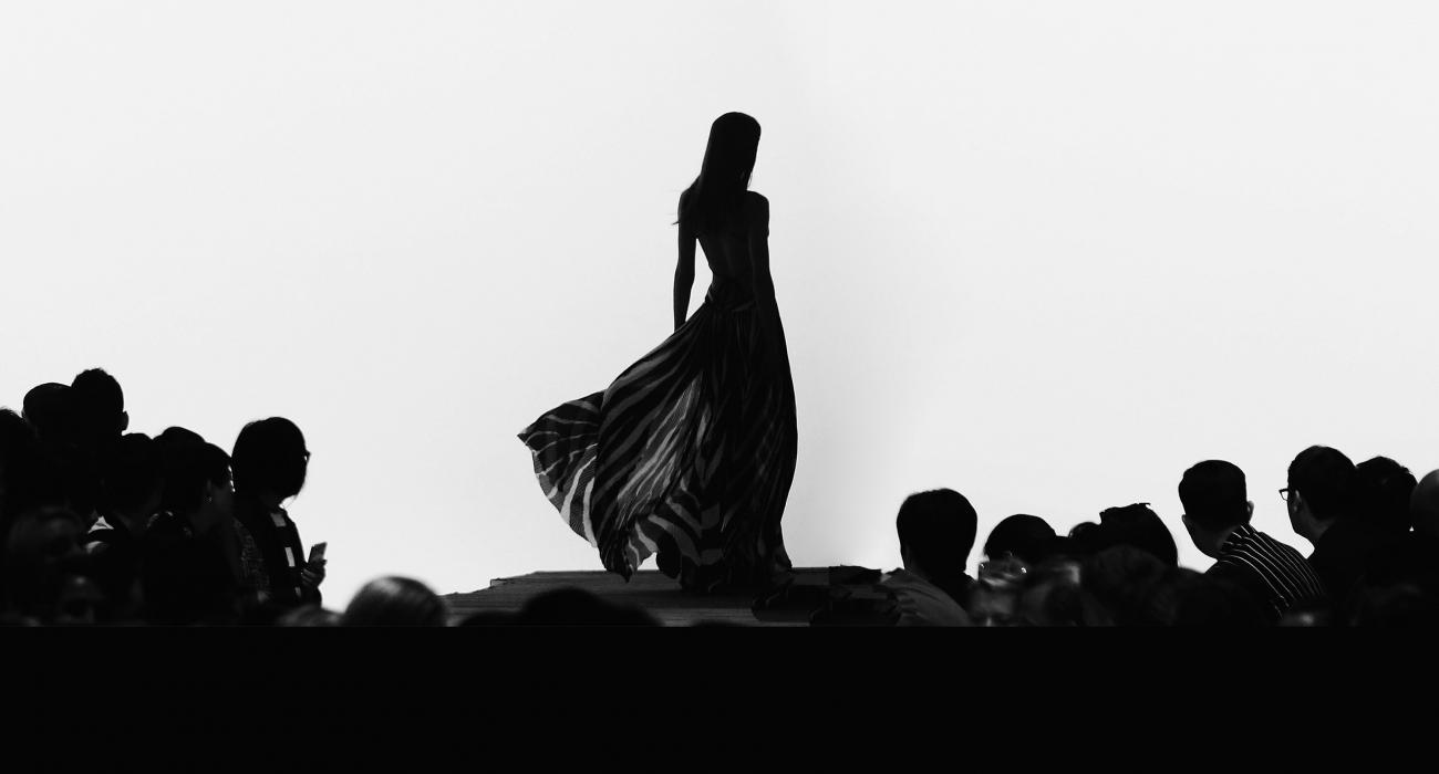 Silhouette of a fashion model on a runway with large audience